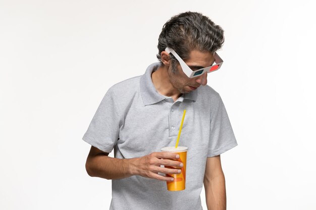 Vista frontal hombre joven sosteniendo soda en gafas de sol d en escritorio blanco disfrute de película remota solitario