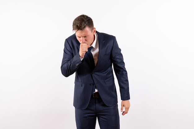 Vista frontal hombre joven tosiendo en traje estricto clásico sobre fondo blanco emociones modelo de moda humana traje masculino