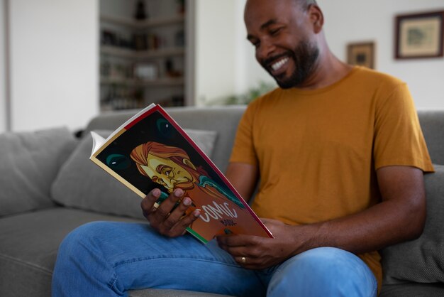 Vista frontal hombre leyendo cómics en casa