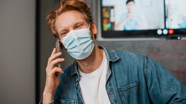 Vista frontal del hombre con máscara y hablando por teléfono