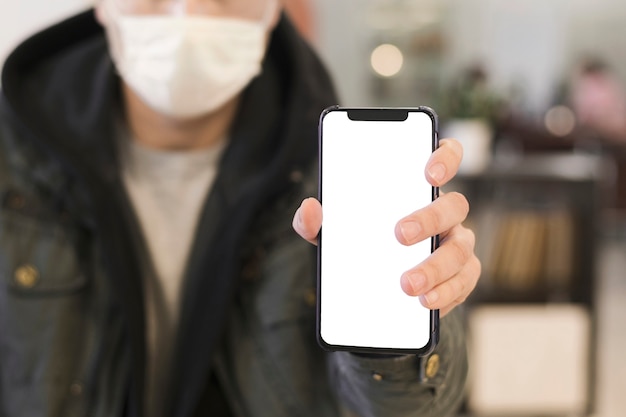 Vista frontal del hombre con máscara médica sosteniendo el teléfono