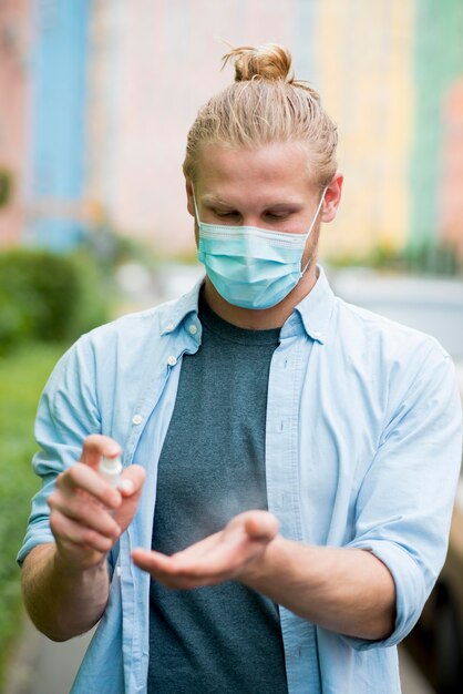 Vista frontal del hombre con mascarilla con desinfectante para manos