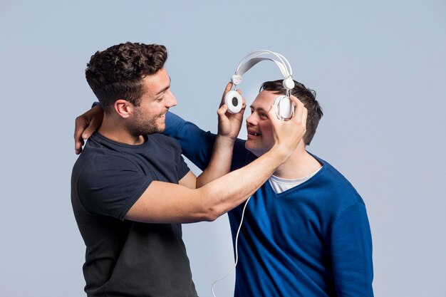 Vista frontal hombre mostrando a su amigo una canción a través de auriculares