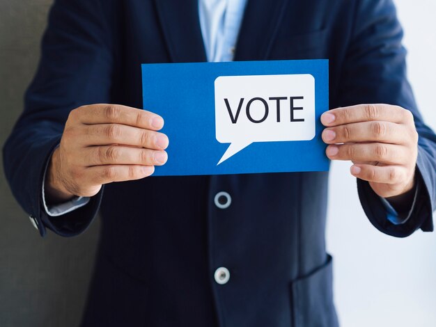 Vista frontal hombre mostrando una tarjeta de votación con un bocadillo