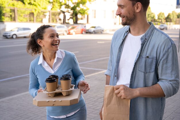 Vista frontal del hombre y la mujer al aire libre con comida para llevar
