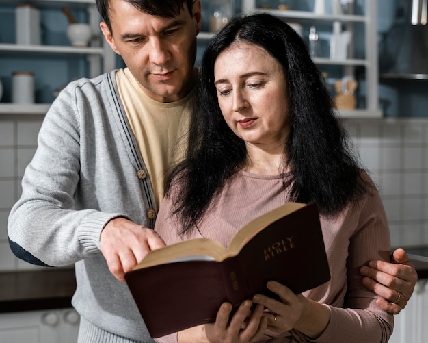 Foto gratuita vista frontal del hombre y la mujer en la cocina leyendo la biblia