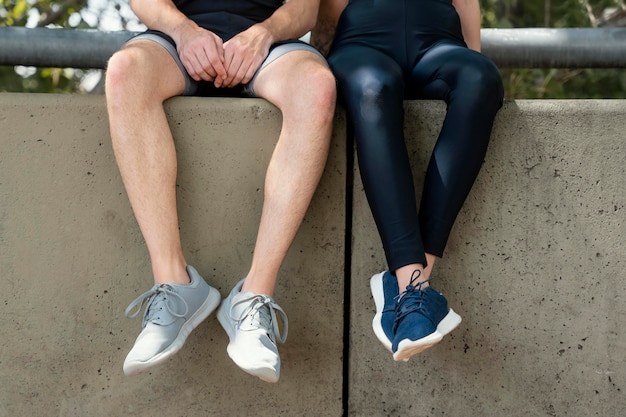 Vista frontal del hombre y la mujer descansando juntos al aire libre mientras hace ejercicio