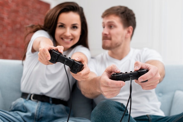 Vista frontal hombre y mujer divirtiéndose mientras juega con controladores