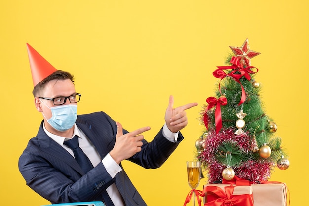 Vista frontal del hombre de negocios apuntando al árbol de Navidad y presenta en amarillo