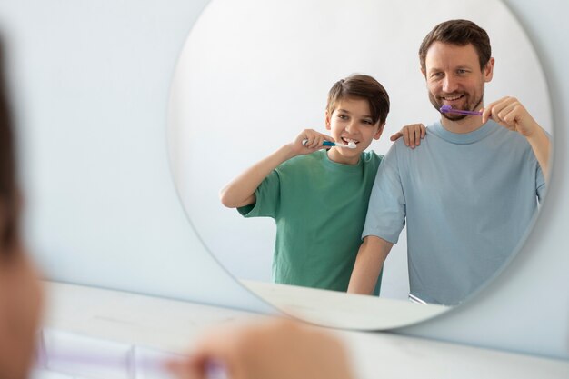 Vista frontal hombre y niño cepillandose los dientes