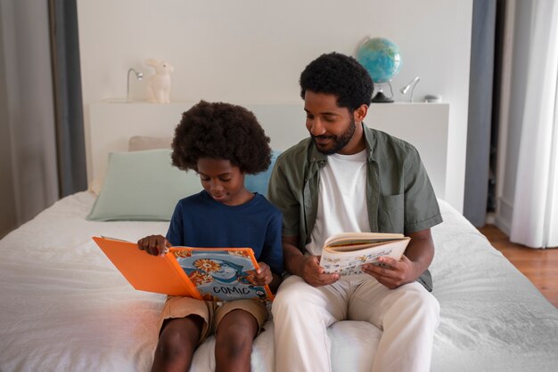 Vista frontal hombre y niño leyendo cómics en casa