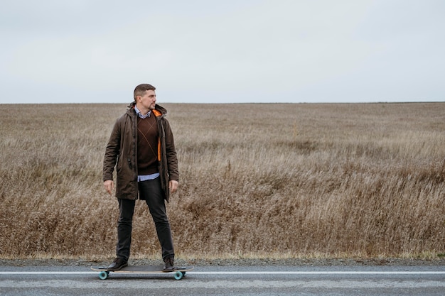 Vista frontal del hombre con patineta en la carretera