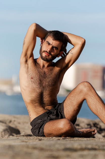 Vista frontal hombre con pecho peludo en la playa