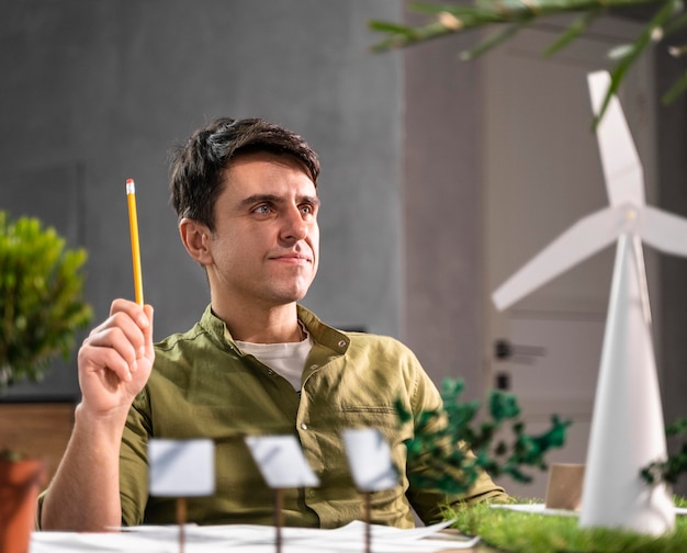Foto gratuita vista frontal del hombre pensando en un proyecto de energía eólica ecológica con turbinas eólicas