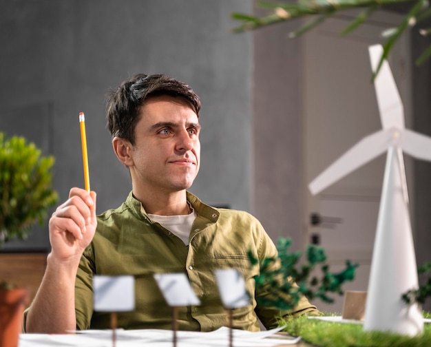 Vista frontal del hombre pensando en un proyecto de energía eólica ecológica con turbinas eólicas