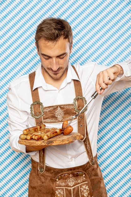 Vista frontal del hombre con plato de salchichas alemanas