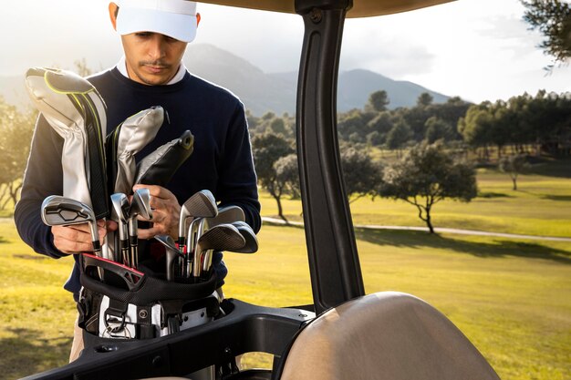 Vista frontal del hombre poniendo palos en carrito de golf