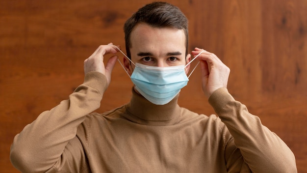 Vista frontal del hombre poniéndose mascarilla médica