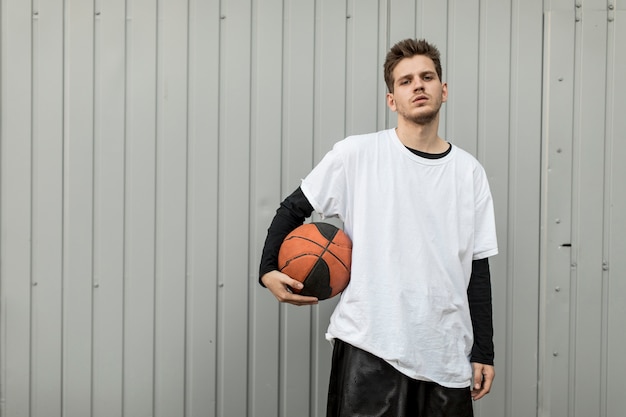 Vista frontal hombre posando con una pelota de baloncesto