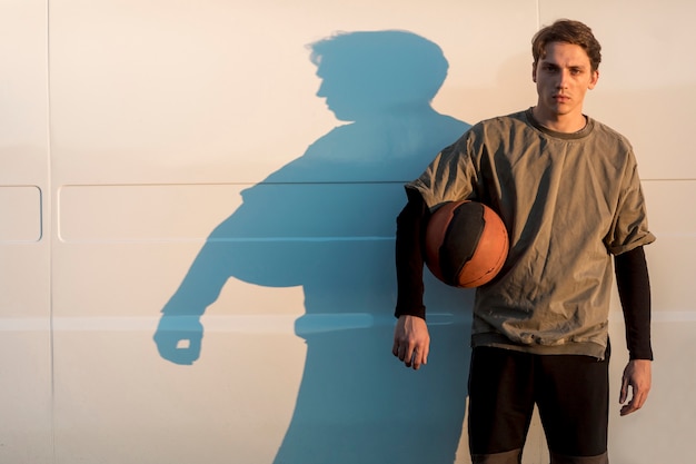 Vista frontal hombre posando con una pelota de baloncesto