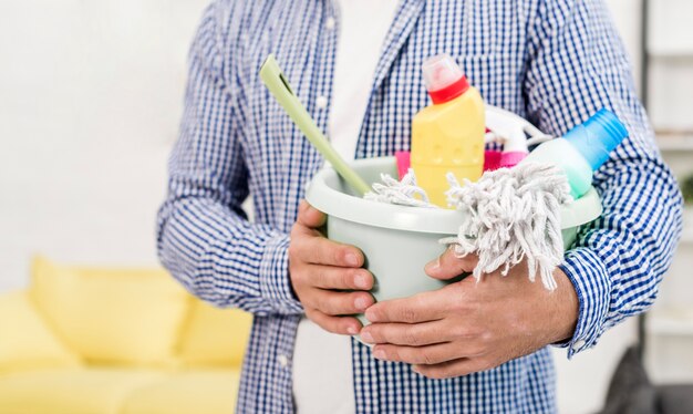 Vista frontal del hombre con productos de limpieza en balde