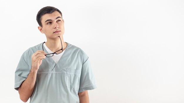 Vista frontal del hombre que sostiene sus gafas en la barbilla como si estuviera pensando