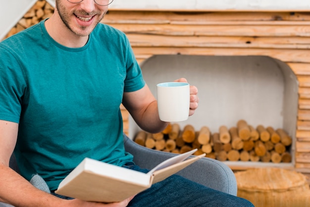 Foto gratuita vista frontal del hombre que sostiene la taza y el libro