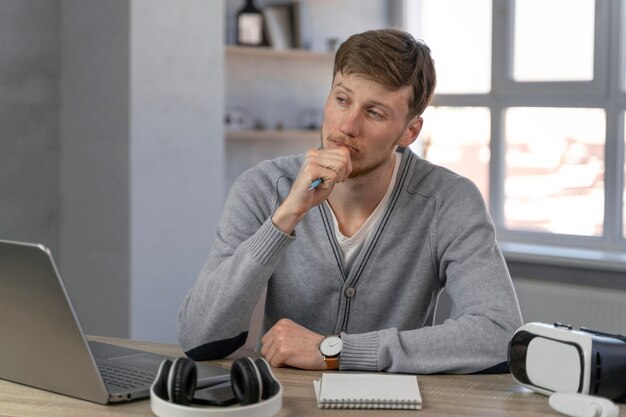 Vista frontal del hombre que trabaja en el campo de los medios de comunicación con una computadora portátil y auriculares