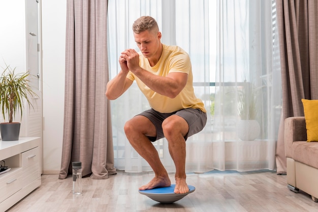 Vista frontal del hombre que trabaja en casa con bosu ball