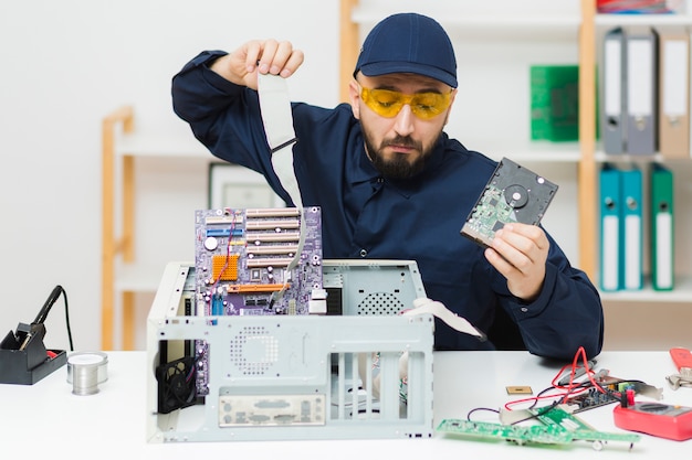 Vista frontal hombre reparando una computadora