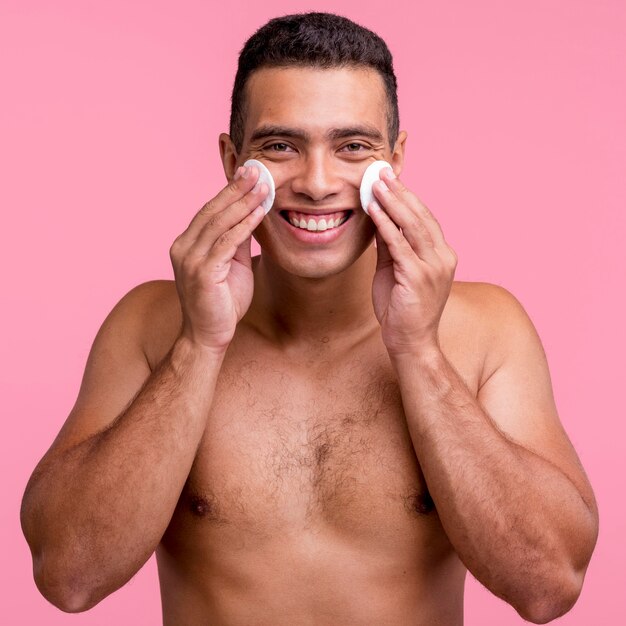 Vista frontal del hombre sonriente con almohadillas de algodón en su rostro