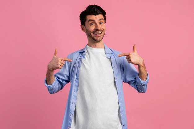 Vista frontal del hombre sonriente apuntando a sí mismo