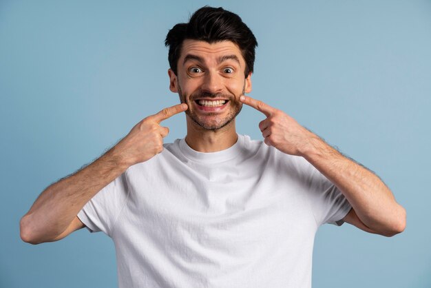 Vista frontal del hombre sonriente apuntando a su sonrisa