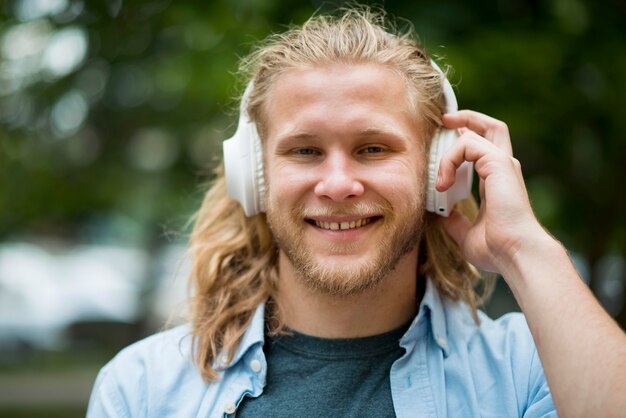 Vista frontal del hombre sonriente con auriculares al aire libre