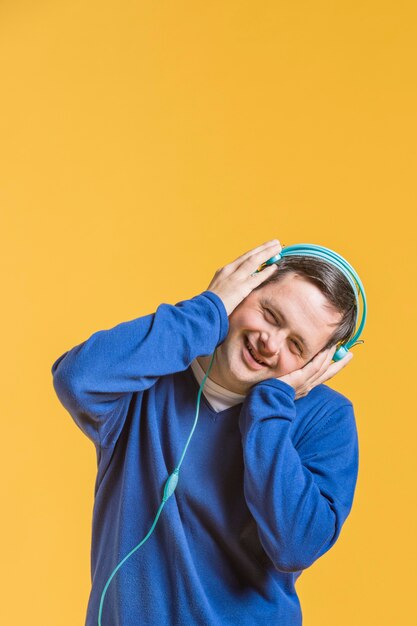 Vista frontal del hombre sonriente escuchando música con auriculares