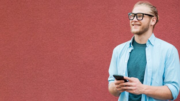 Vista frontal del hombre sonriente con espacio de copia y teléfono inteligente