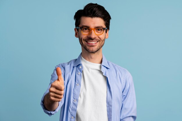 Vista frontal del hombre sonriente con gafas mostrando los pulgares para arriba