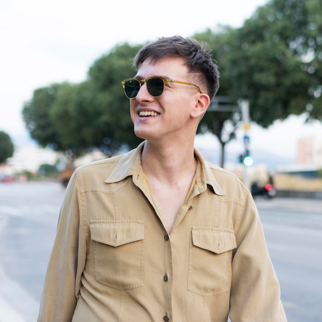 Vista frontal del hombre sonriente con gafas de sol en la ciudad