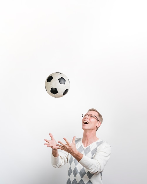 Vista frontal del hombre sonriente jugando con una pelota de fútbol