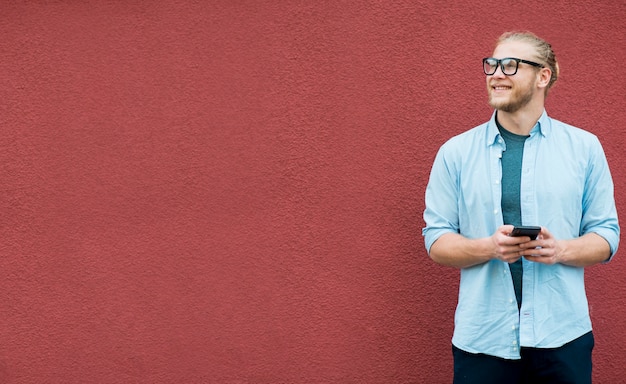 Vista frontal del hombre sonriente con smartphone y copia espacio