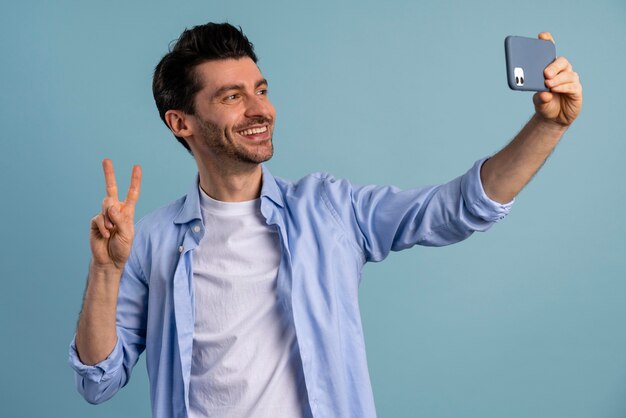 Vista frontal del hombre sonriente tomando un selfie con smartphone