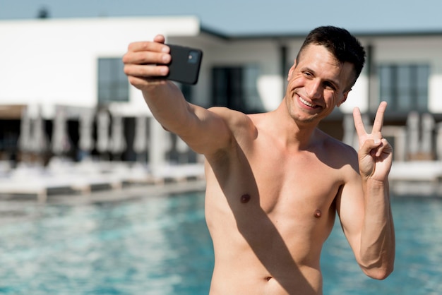 Vista frontal del hombre sonriente tomando un selfie