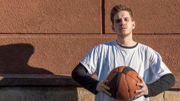 Vista frontal hombre sosteniendo una pelota de baloncesto