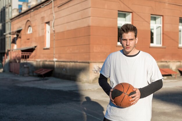 Vista frontal hombre sosteniendo una pelota de baloncesto