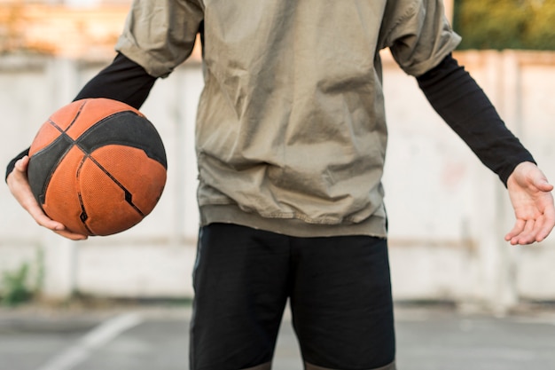 Vista frontal hombre sosteniendo una pelota de baloncesto