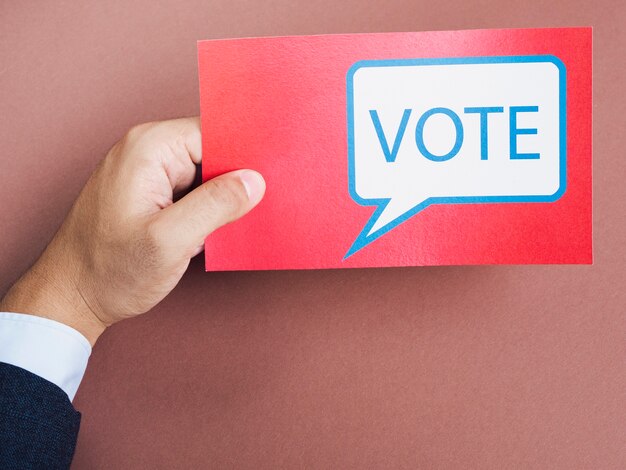 Vista frontal hombre sosteniendo una tarjeta roja con bocadillo de votación