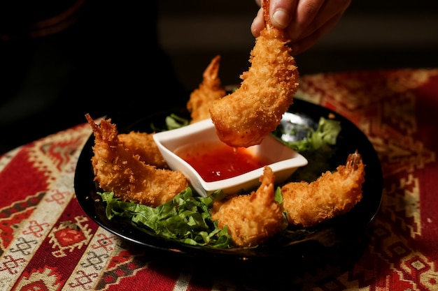 Vista frontal hombre sostiene camarones rebozados con salsa en un plato