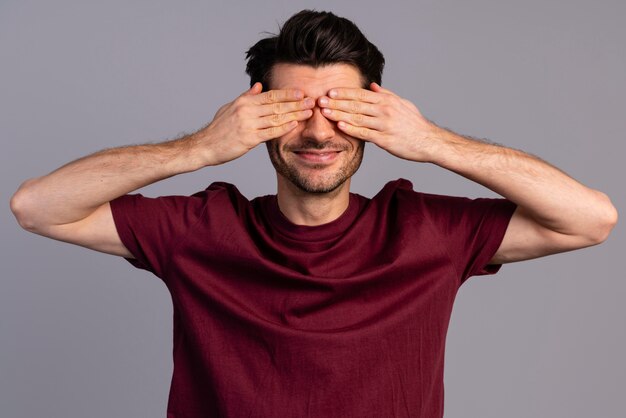 Vista frontal del hombre tímido tapándose los ojos con las manos