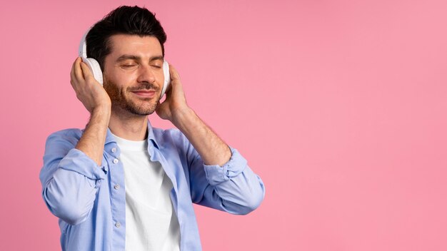 Vista frontal del hombre tocando música a través de sus auriculares