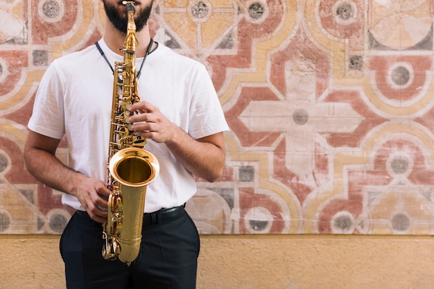 Foto gratuita vista frontal hombre tocando el saxo con fondo geométrico